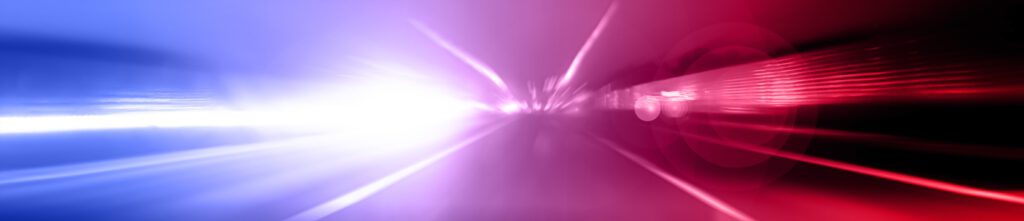 A thin, horizontal rectangular image, with an abstract, slightly distorted view of a police car lights activated. Streaks of bold red, deep blue, and bright white fill the image. You can sense the urgency.