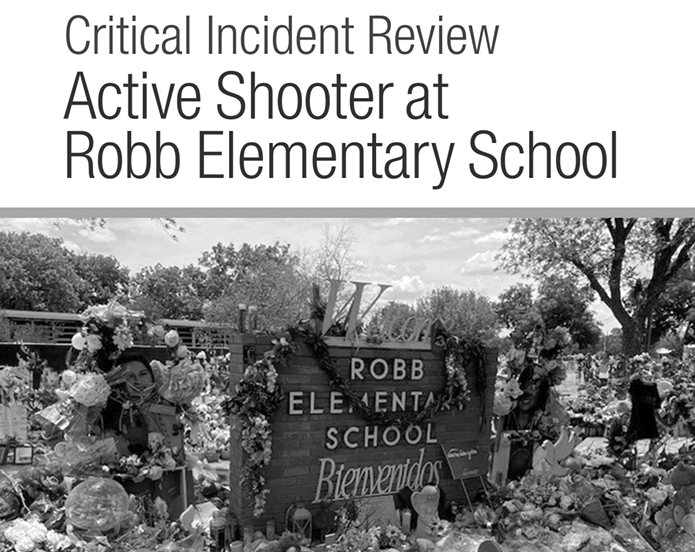 The Uvalde School Shooting Response DOJ Report title page. It reads "Critical Incident Review | Active Shooter at Robb Elementary School. The photo is in black and white, showing the school entrance sign with the words Welcome and Bienvenidos (welcome in Spanish). An ocean of floral arrangements, bouquets, crosses, and pictures adorn the area. Symbols of love and grief left from family and friends.